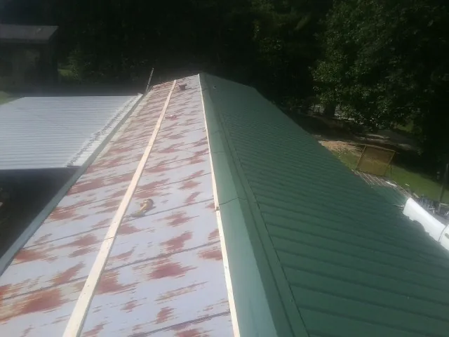 Old rusted panels beside newly installed green metal roofing — Wind Damage Roof Repair by Roofing Brothers in Streamwood