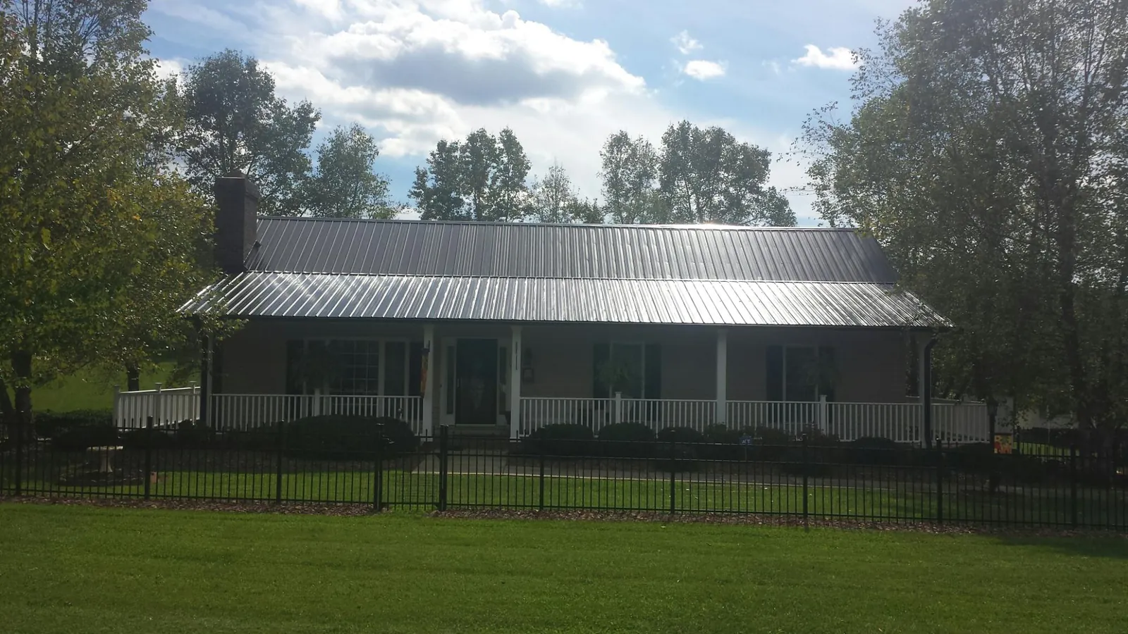 Gray metal roof on a brick ranch with a full width front porch — Gutter Guard Installation work by our crew in Streamwood