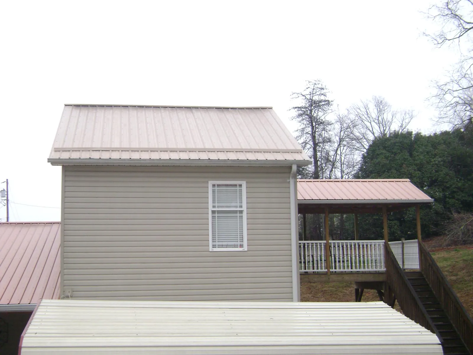 Tan metal roofs on a two story addition and attached porch, from a Roof Replacement job in Streamwood