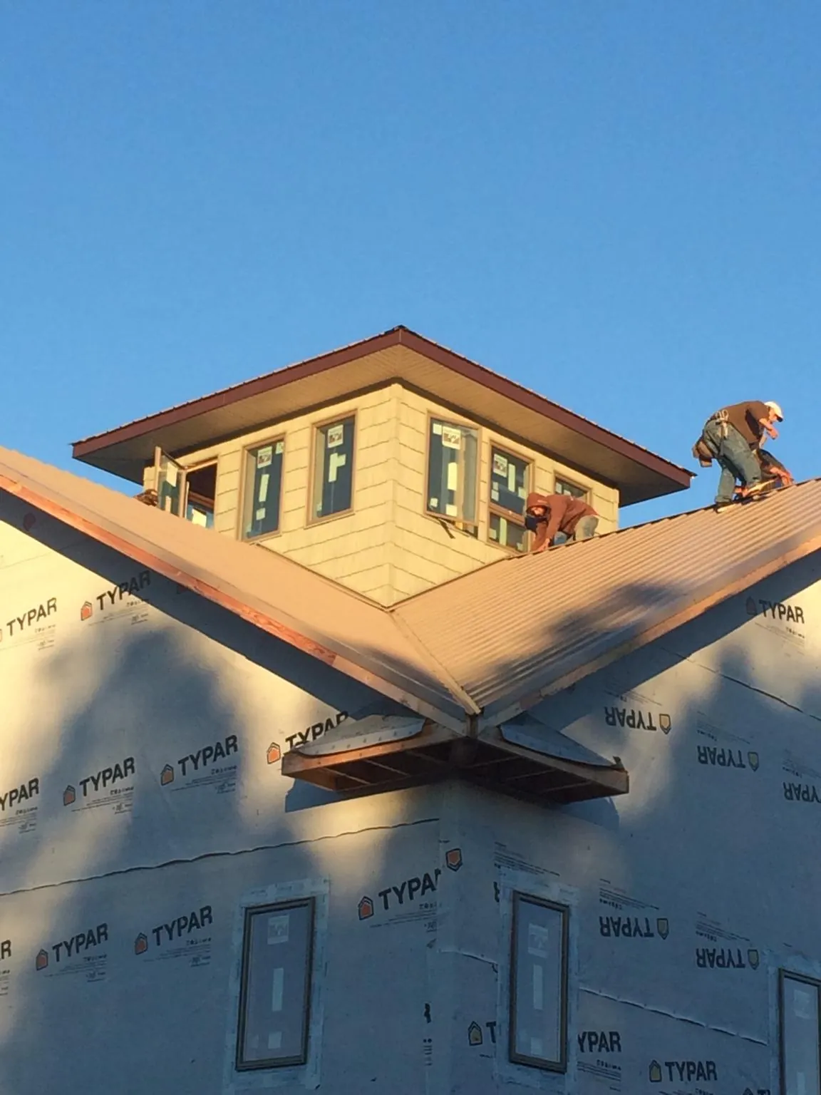 Roofers working around a rooftop cupola on a new metal roof at sunset — Roof Waterproofing in Streamwood by Roofing Brothers